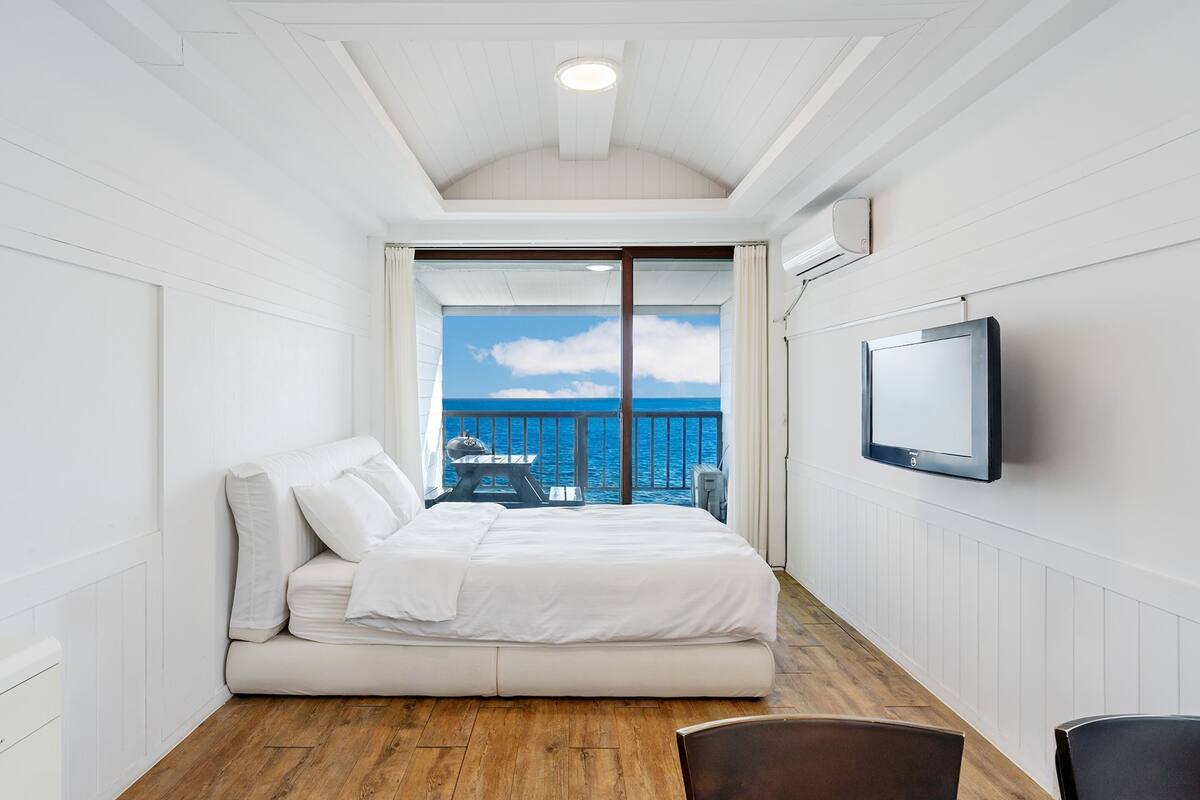 Une chambre avec un lit, une télévision et une vue sur la mer.