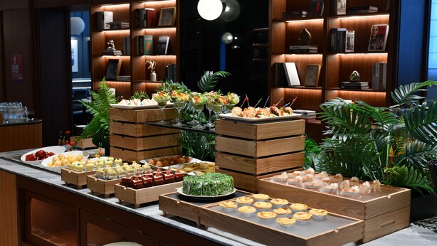 A buffet with various food items and a bookshelf in the background. - IntercityHotel Shenzhen Huaqiang North (Shenzhen)