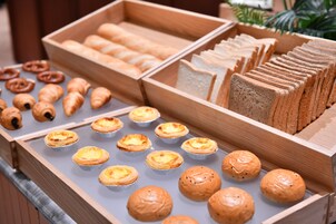 A variety of baked goods including pastries and bread in wooden display cases.