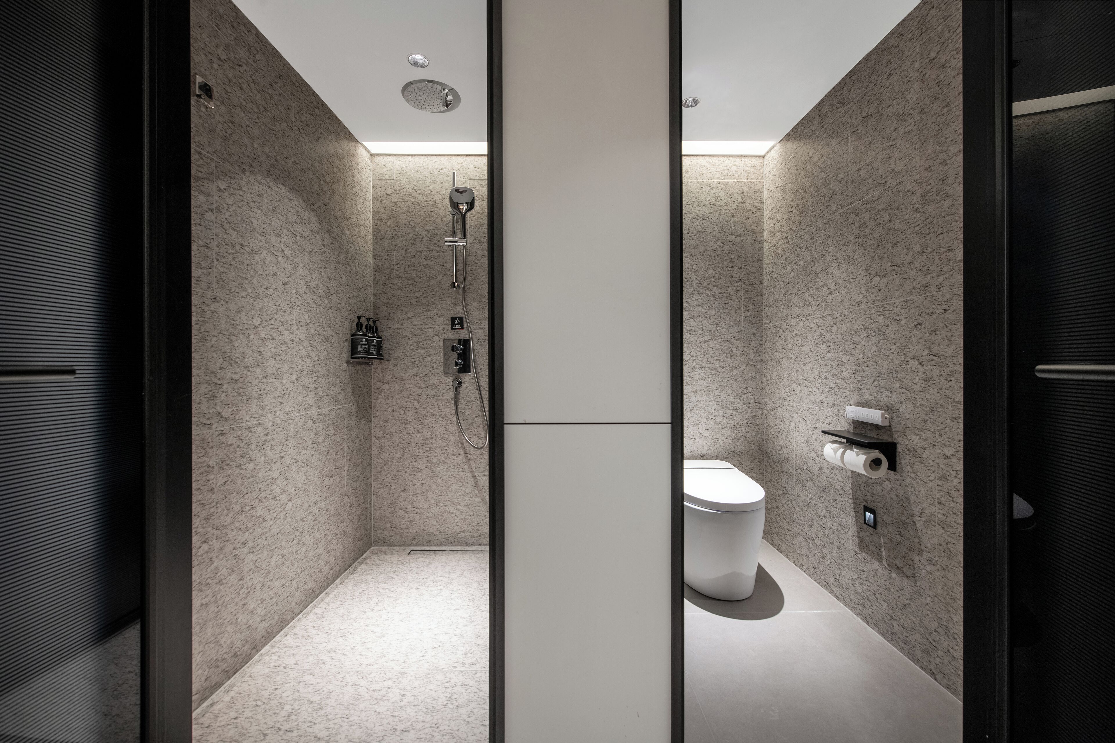 A modern bathroom with a shower, toilet, and towel rack.