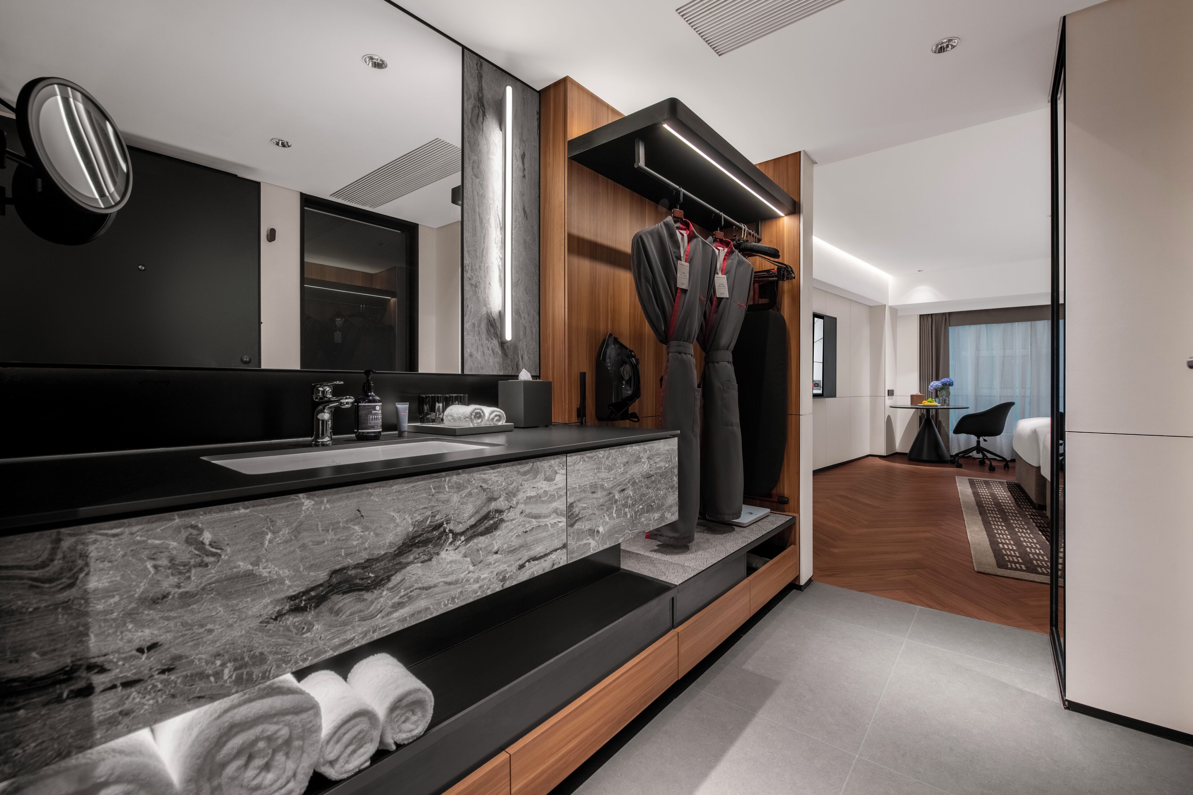 A modern bathroom with a marble sink, wooden vanity, and a large mirror.