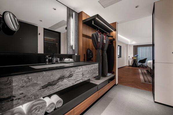 Un baño moderno con lavamanos de mármol, tocador de madera y un espejo grande.