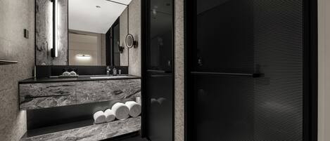 A modern bathroom with a marble vanity, a large mirror, and a towel rack.
