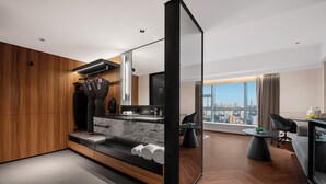 A modern hotel room with a wooden floor, a large window with a city view, a black sofa, a dining table, and a large mirror. - IntercityHotel Shenzhen Huaqiang North (Shenzhen)