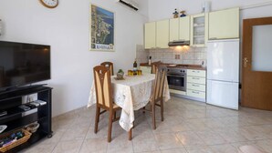 Μια μικρή, λειτουργική κουζίνα με τραπεζαρία, τηλεόραση και ένα ρολόι στον τοίχο.