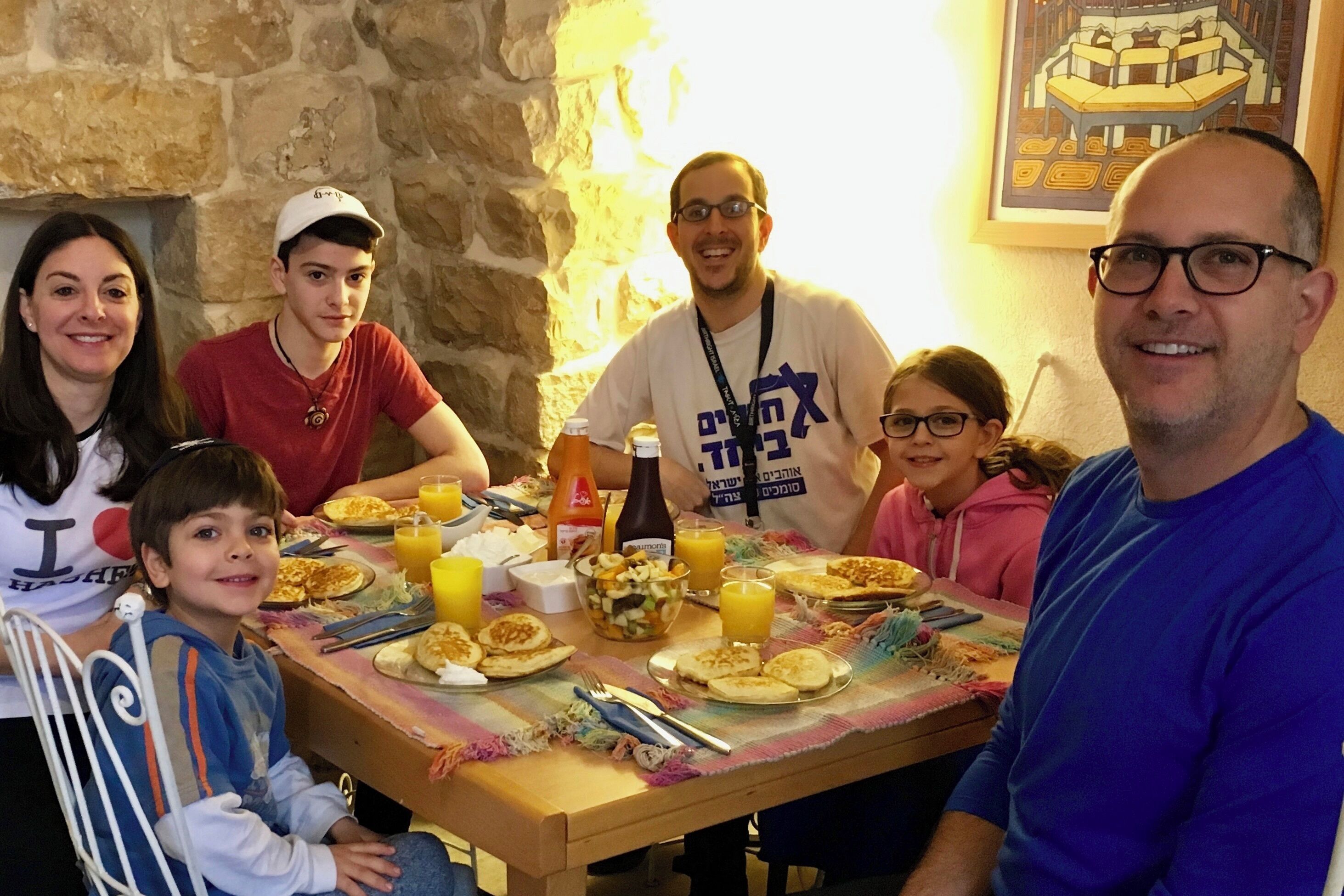 A family dining at a table with a stone wall background.