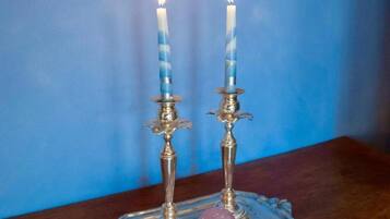 Deux bougies allumées sur un plateau en argent, accompagnées d’un objet décoratif.