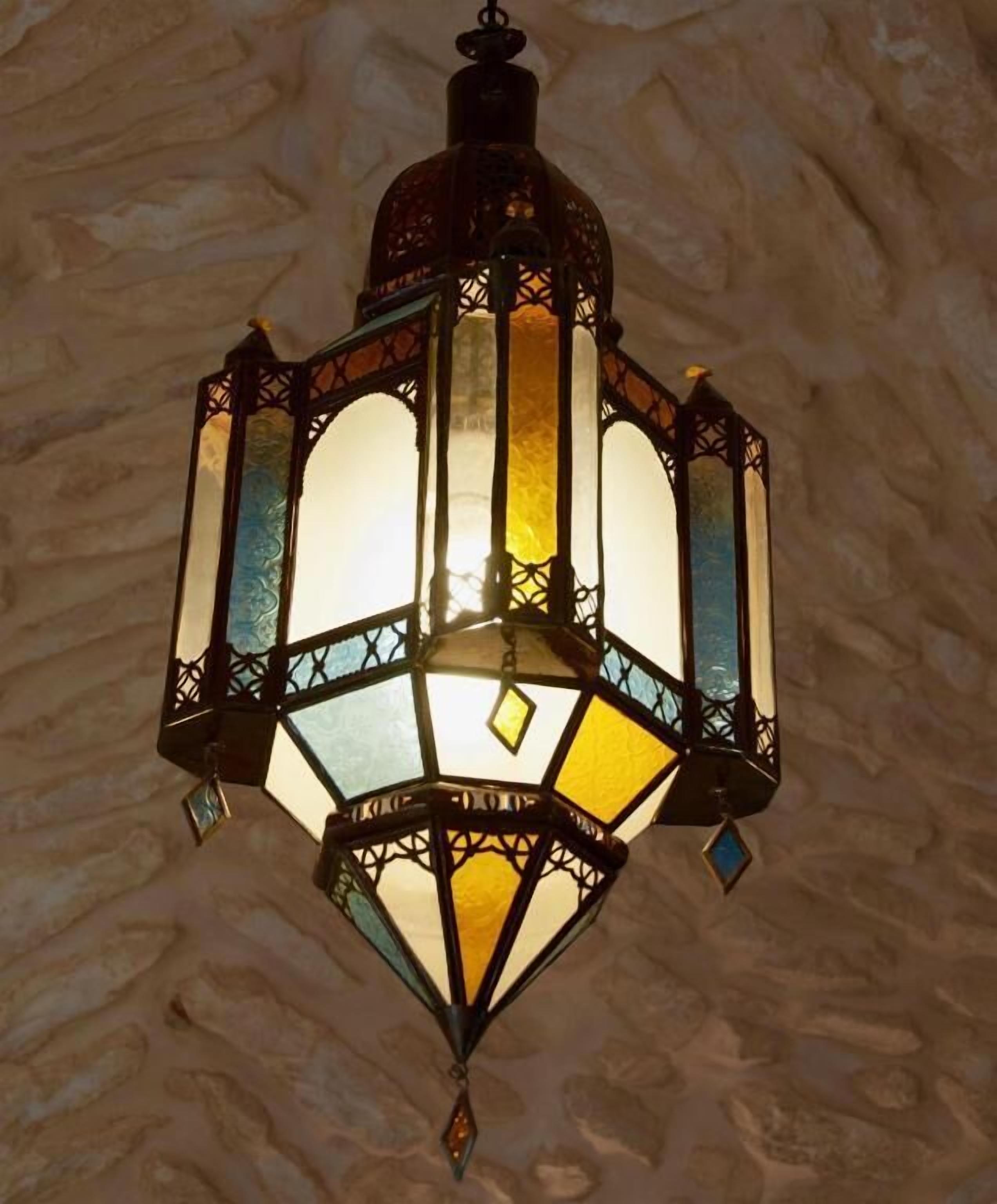 A traditional lantern with a geometric design, hanging from a ceiling with a textured stone wall.