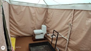 Ein Badezimmer mit Zeltdach, Toilette und einem kleinen schwarzen Waschbecken.