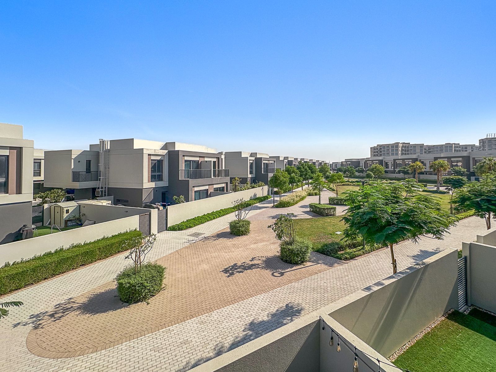 Een modern wooncomplex met een verharde looppad, groenvoorziening en moderne architectuur.