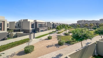 Een modern wooncomplex met een verharde looppad, groenvoorziening en moderne architectuur.