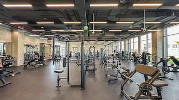 Een ruime fitnessruimte met diverse fitnessapparaten, grote ramen en een modern plafondontwerp.