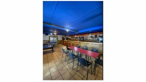 Een bar met tafels en stoelen, een pooltafel en een toog met krukken.