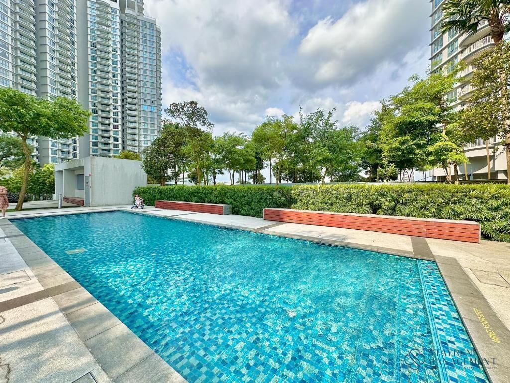 Una piscina rodeada de vegetación y edificios altos.