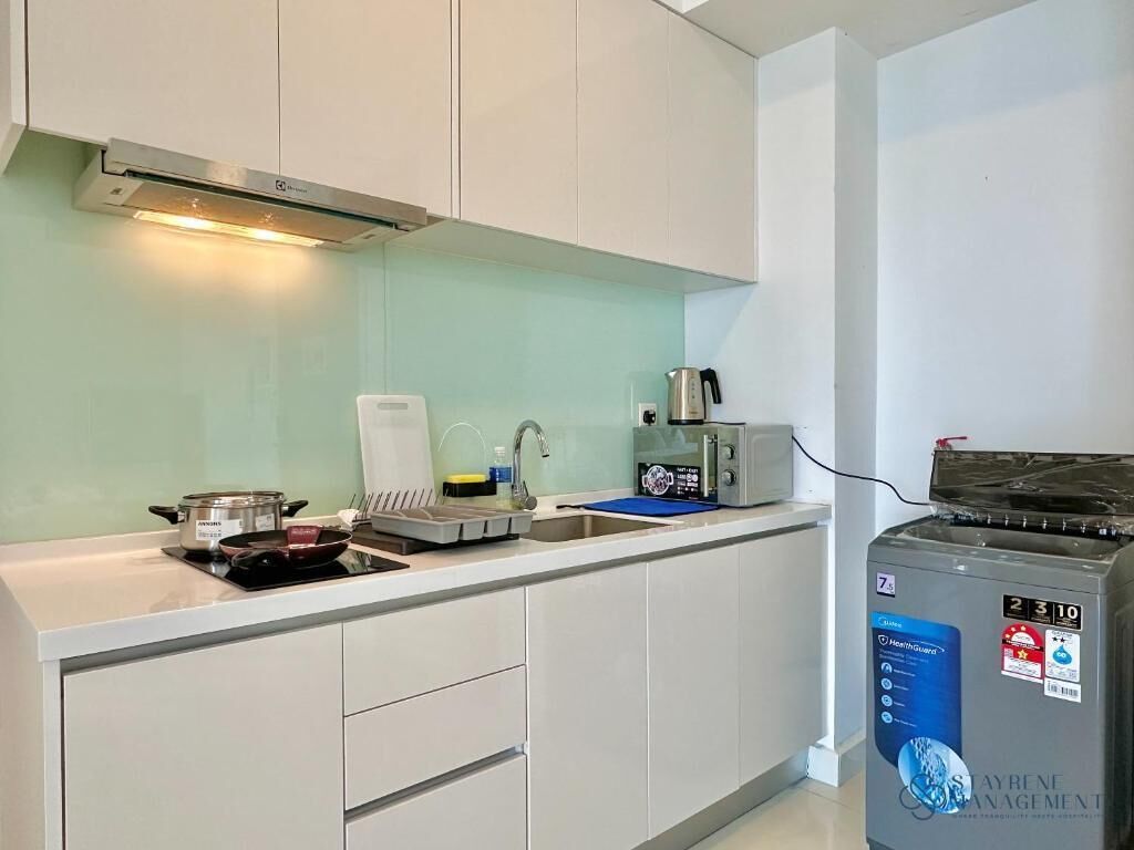 A kitchen with white cabinets, a stove, a microwave, and a water dispenser.