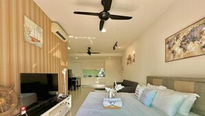 Ein Hotelzimmer mit Bett, Fernseher, Deckenventilator und einem Gemälde an der Wand.