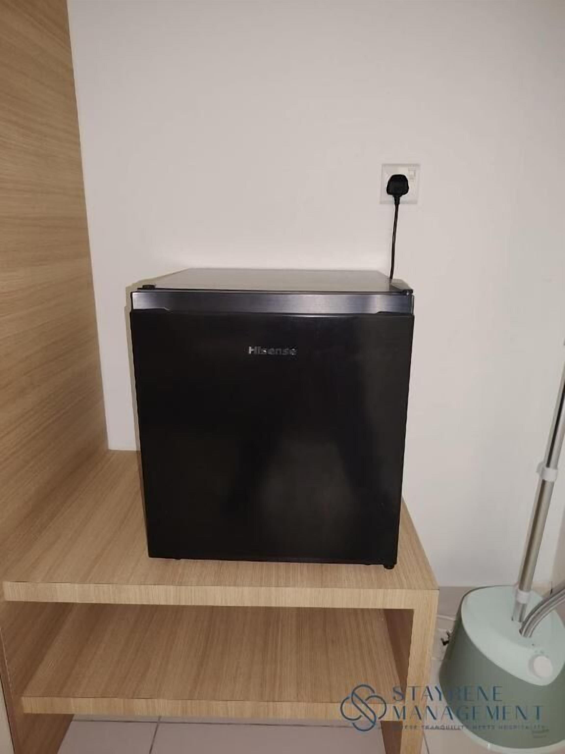 A black portable heater on a wooden shelf in a room with white walls.