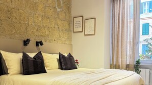 Ein Schlafzimmer mit einem großen Bett, einer Steinwand und einem Fenster mit Vorhängen.