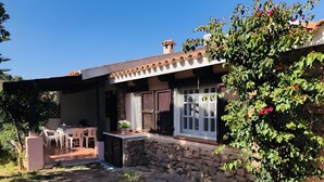 A house with a patio, stone walls, a wooden door, and a window. - Bouganville Two-Room Apartment 80 m from the Beach with Private Terrace, Garden & AC (Porto Taverna)