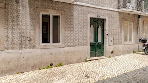 A building with patterned exterior walls, a green door, and a cobblestone street. - Cosy Loft Heart Of The City! (Lisboa)