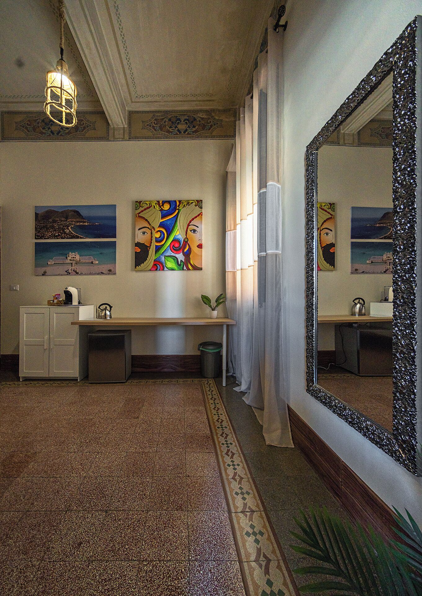 A hotel bathroom with a large mirror, a sink, a cabinet, a potted plant, and artwork on the walls.