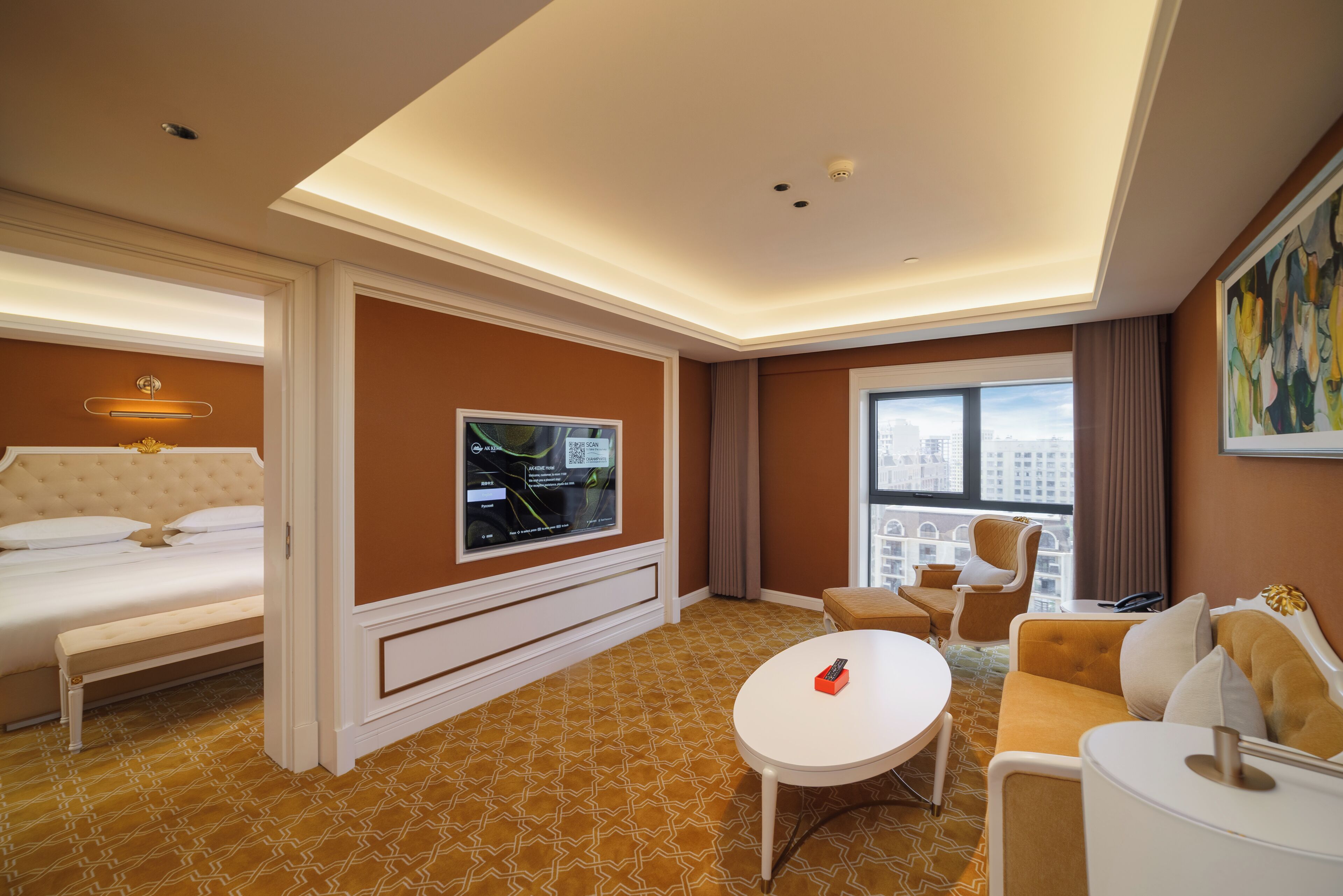 Une chambre d’hôtel équipée d’un lit, d’une télévision, d’un canapé, d’une table basse et offrant une vue sur la ville.