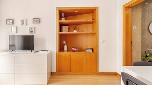 Ein modernes Wohnzimmer mit einer weißen Unterhaltungseinheit, einem Holzschrank mit Regalen und einem Fernseher.