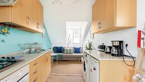 A compact kitchen with wooden cabinets, a stove, a washing machine, and a coffee maker. - Trendy Loft Heart Of The City! (Lisboa)