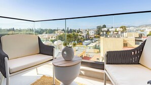 En balkon med to stole, et lille bord og udsigt over bybilledet.