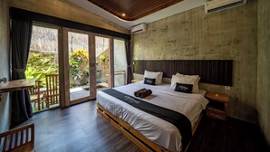 A modern hotel room with a large bed, a wooden desk, and a balcony with plants. - dedeane ubud (Ubud)
