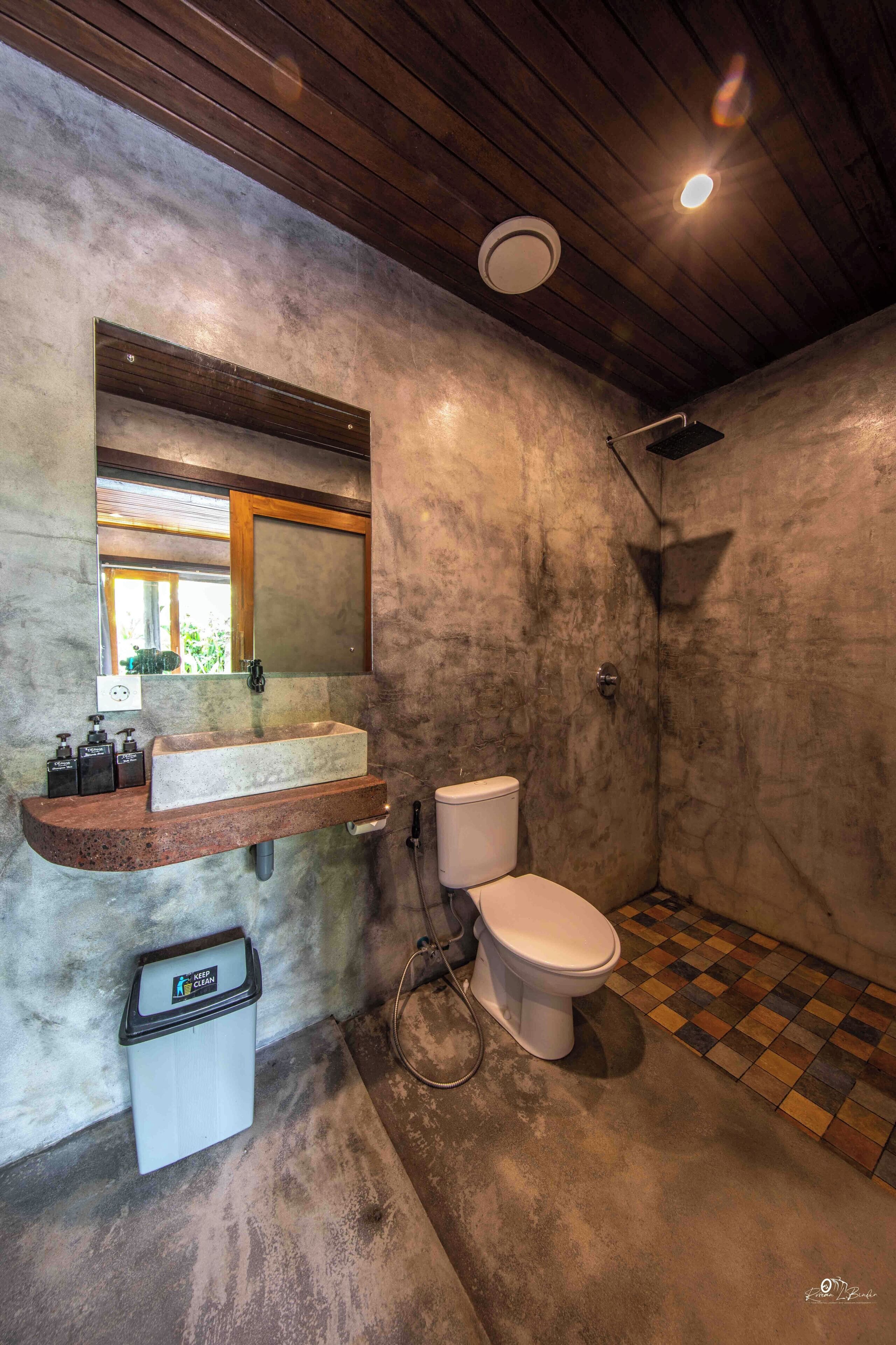 A bathroom with a stone sink, a toilet, and a shower.