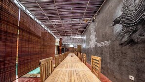 A long wooden table with chairs, a mural on the wall, and a ceiling with a grid pattern. - dedeane ubud (Ubud)