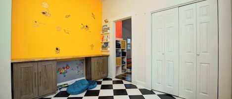 Una habitación infantil con suelo a cuadros, un armario y una estantería llena de libros.