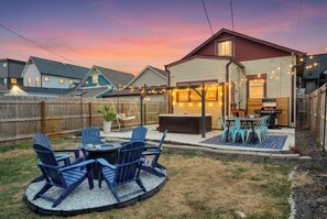 A backyard with a barbecue area, outdoor seating, and a hot tub.