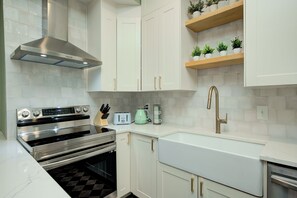 A modern kitchen with white cabinetry, stainless steel appliances, and a built-in oven.