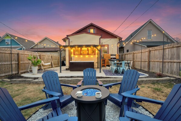 A backyard with a barbecue area, outdoor seating, and a hot tub.