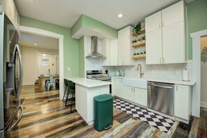 A modern kitchen with white cabinetry, a stainless steel dishwasher, and a checkered floor pattern.