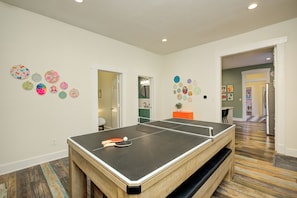 A ping pong table in a room with patterned walls and a wooden floor.