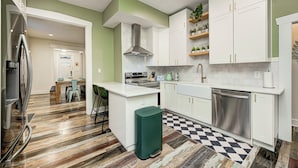 Una cucina moderna con mobili bianchi, un piano cottura in acciaio inossidabile e un pavimento a scacchi.