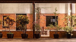 A building with a brick facade, potted plants, and a covered patio area. - Slow Travel Space for Neighbors (Wujie)