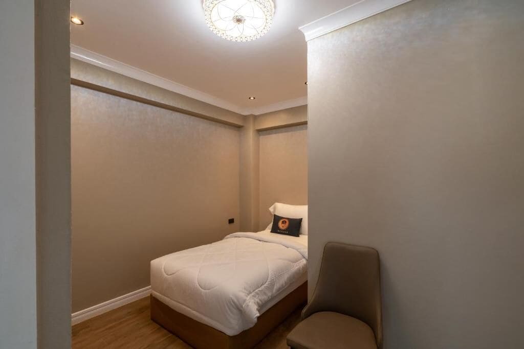 Un dormitorio con cama, una silla y una lámpara en el techo.