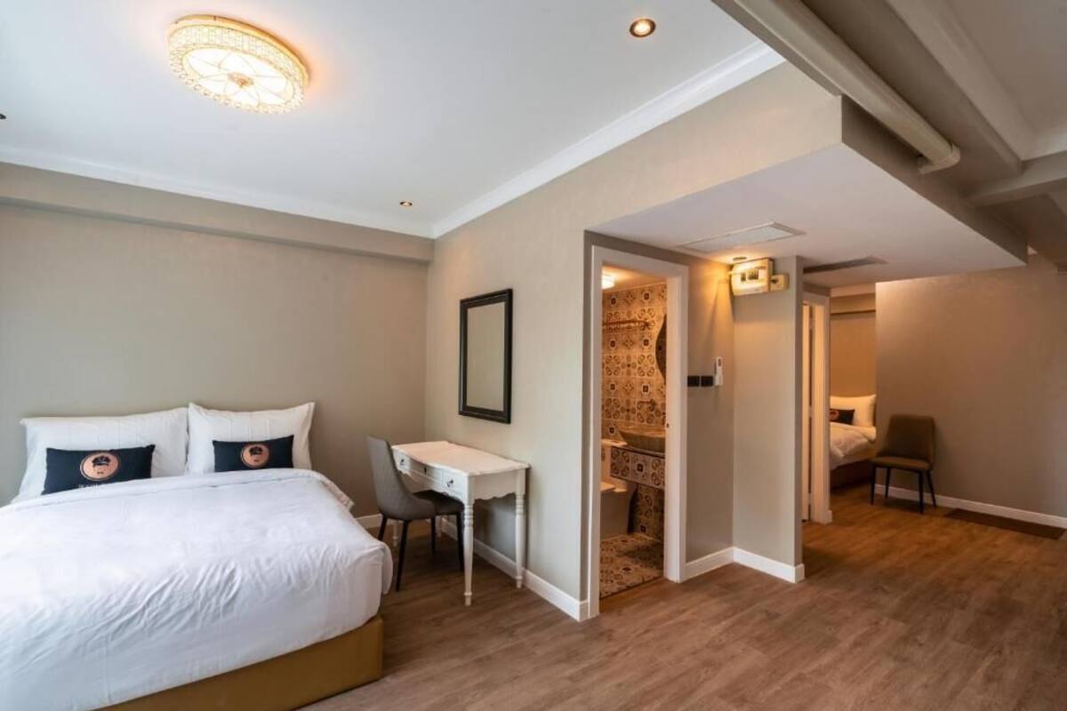A bedroom with a bed, desk, and a small bathroom visible through an open door.