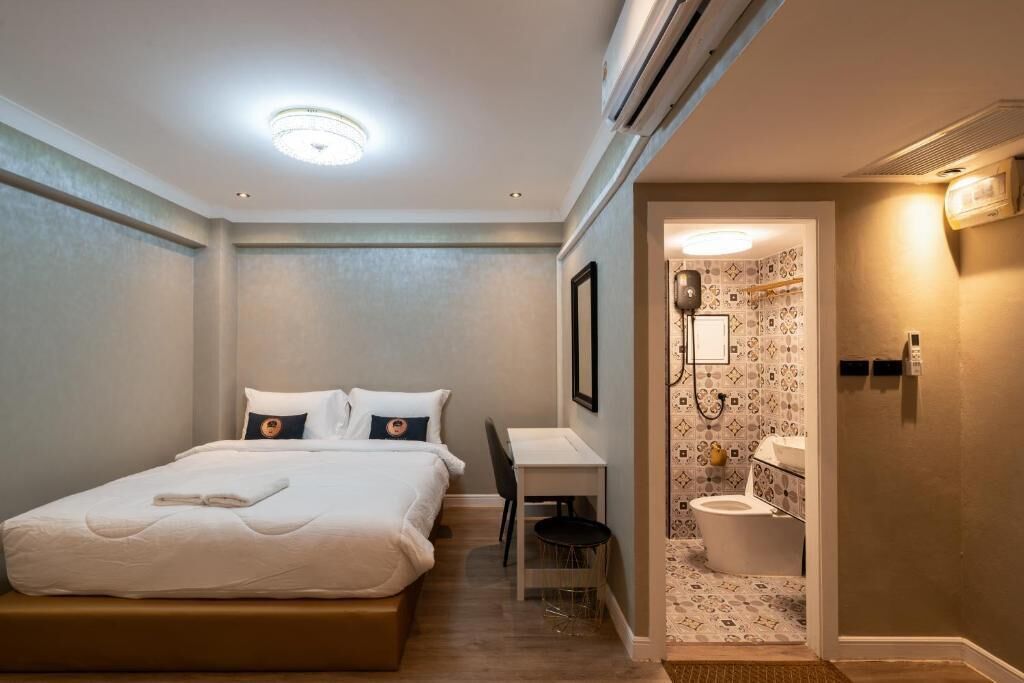 A hotel room with a bed, a desk, and a bathroom.