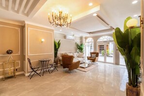 A spacious living area with a chandelier, a coffee table, and comfortable seating. - RQ Timeless Phuket Old Town (Phuket)