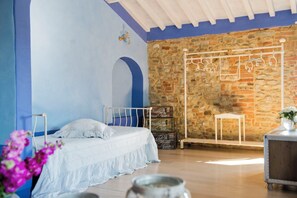 A bedroom with a bed, a stone wall, and a metal rack. - Le Tre Virtù Luxury Relais, Private Pool, Mugello (Scarperia)