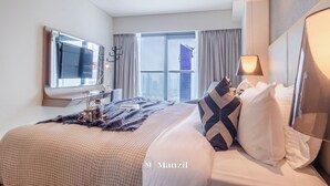 A modern hotel room with a large bed, a flat-screen TV, a large window with curtains, and a city view. - Manzil - High Floor 1BR in Business Bay (Dubai)