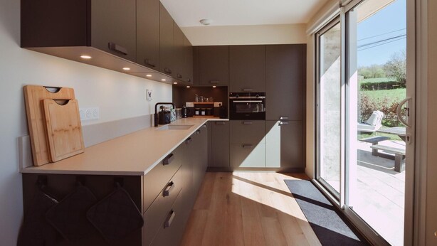 A modern kitchen with a large island, built-in appliances, and a sliding glass door to the outdoors. - Holiday home for 6 people in the heart of Perigord (Saint-Médard-d’Excideuil)