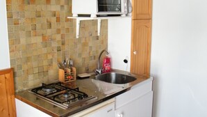 Une cuisine de taille réduite équipée d’une cuisinière à gaz, d’un four à micro-ondes et d’un évier.