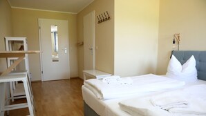 A hotel room with a bed, a bedside table, a chair, a wardrobe, and a door. - Pension Elfmeter (Rheinsberg)