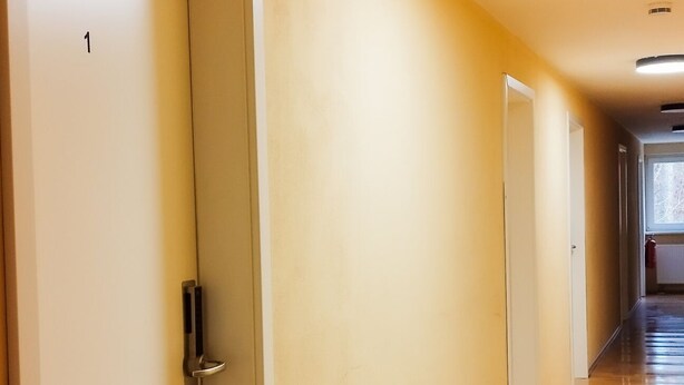 A hallway with wooden flooring, white doors, and recessed ceiling lights. - Pension Elfmeter (Rheinsberg)